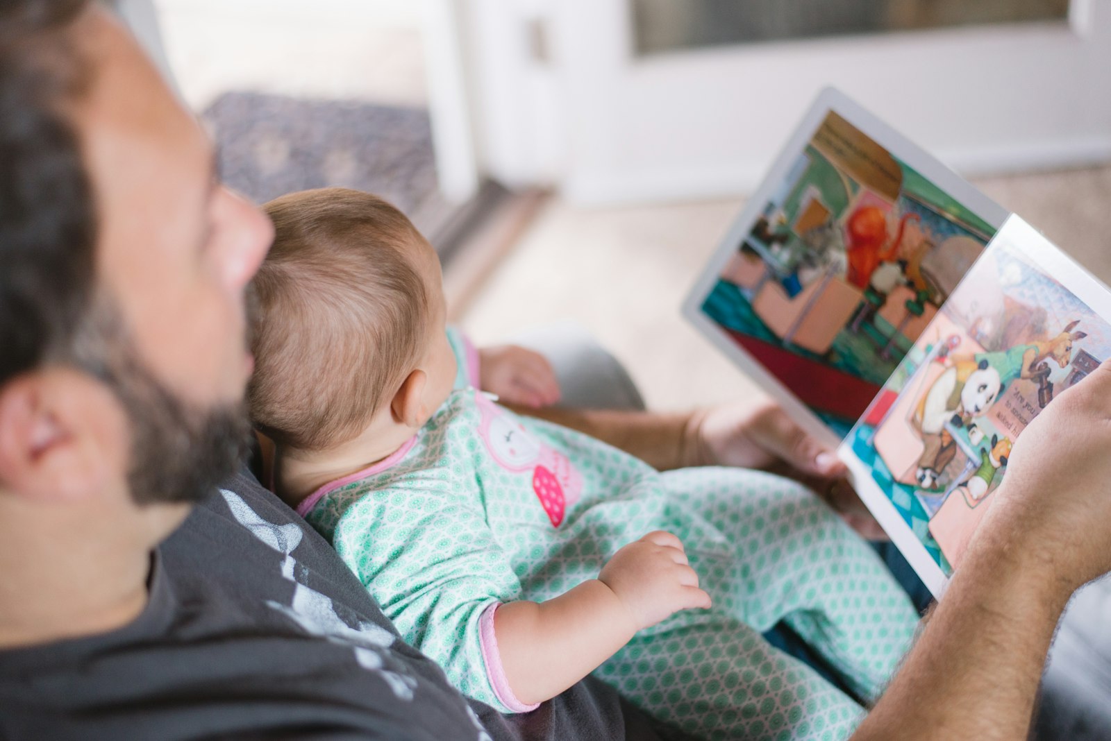 Parent carrying their baby while reading a book