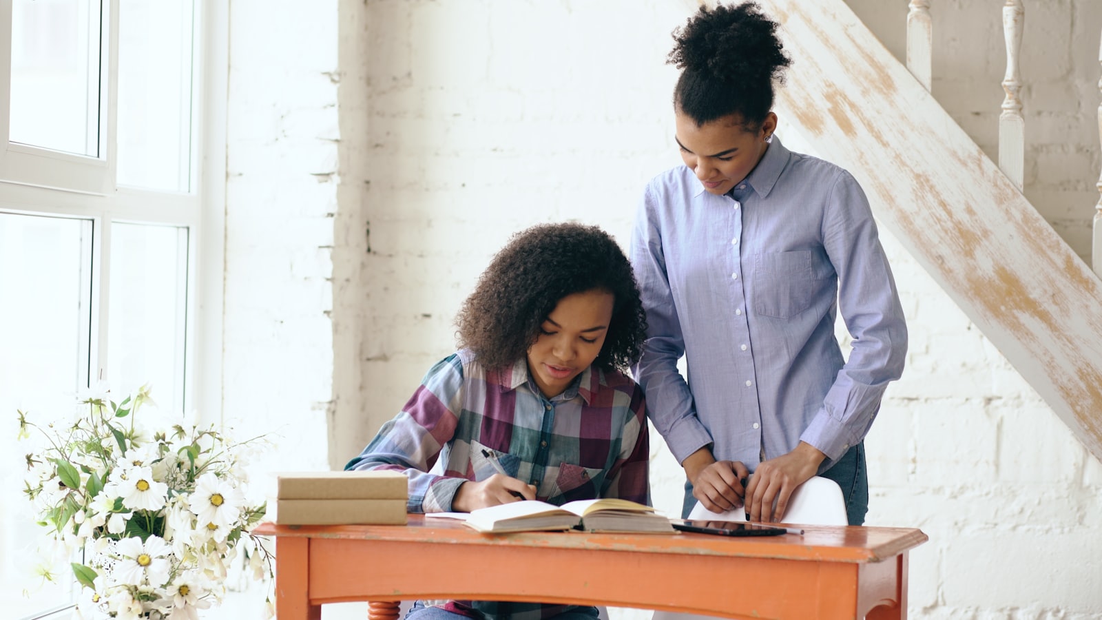 A woman helping a girl with homework at a desk