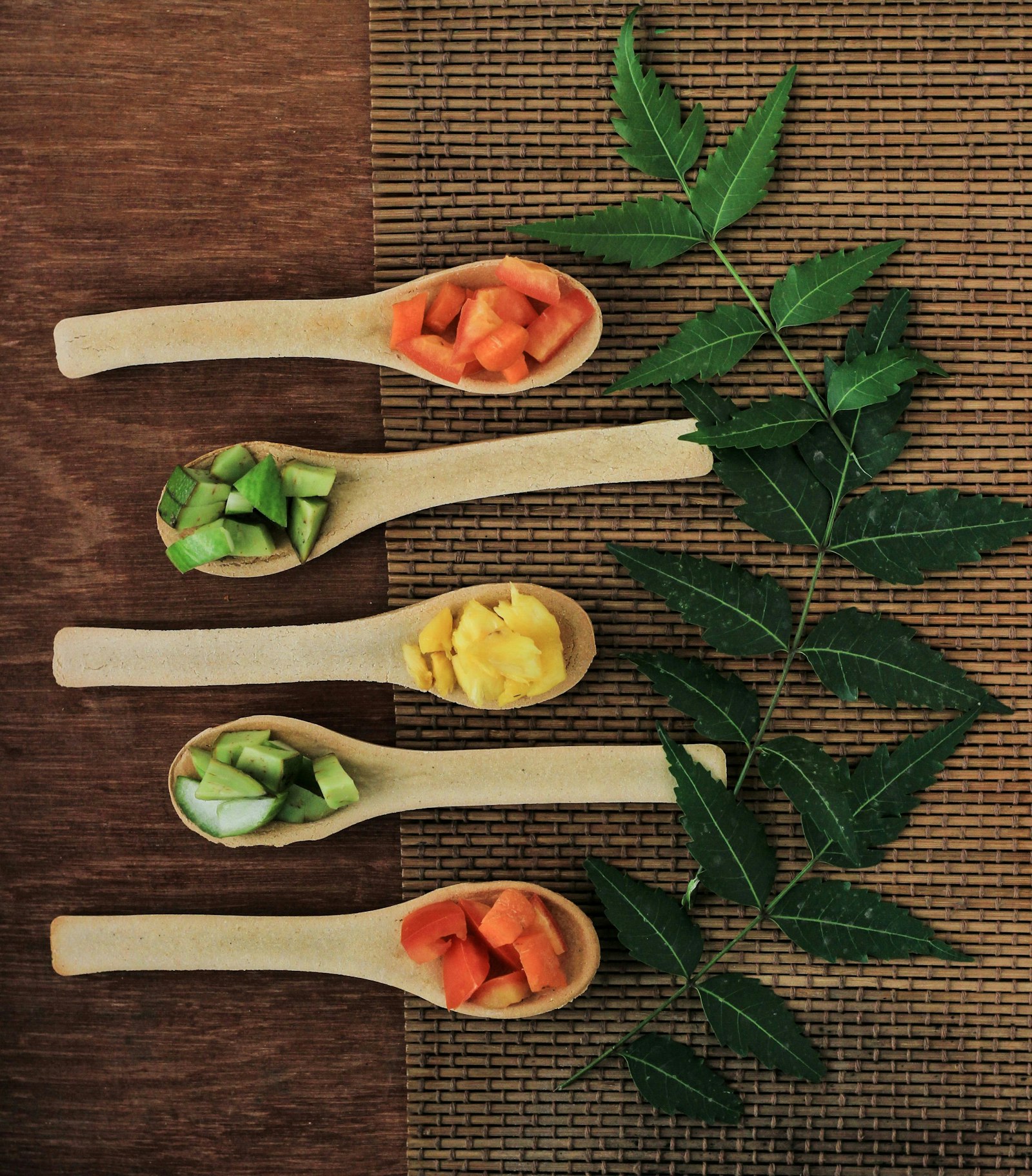 Five wooden spoons filled with different types of colorful baby food