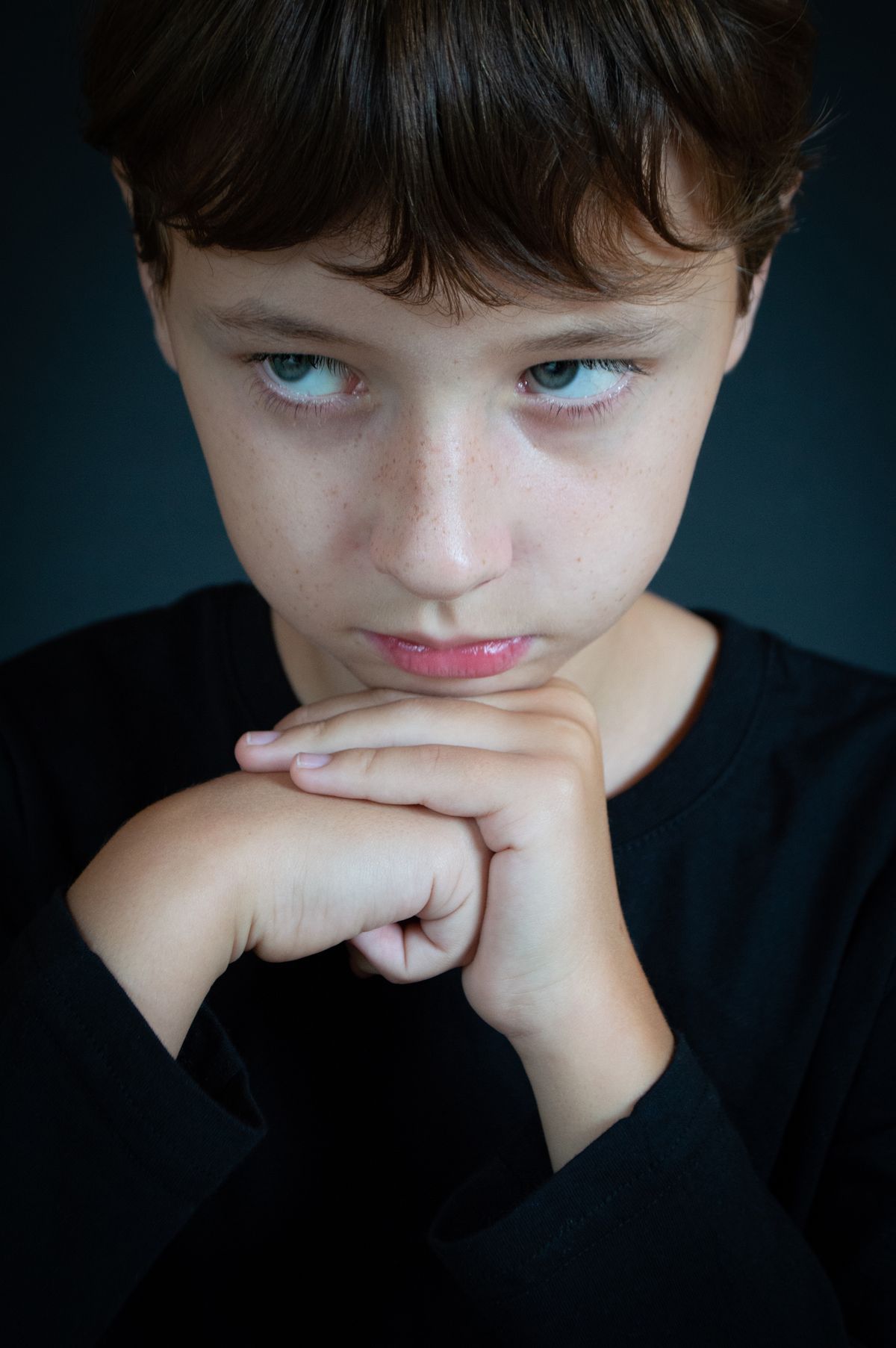 A thoughtful young child resting their chin on their hands