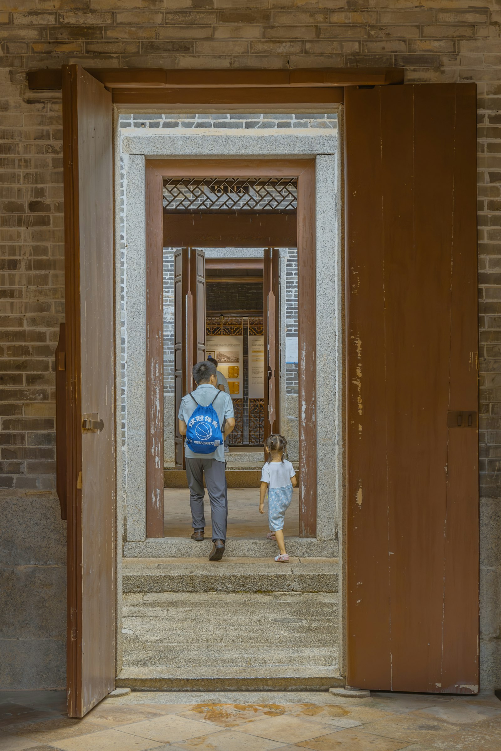 A parent and child walk together through a series of doorways
