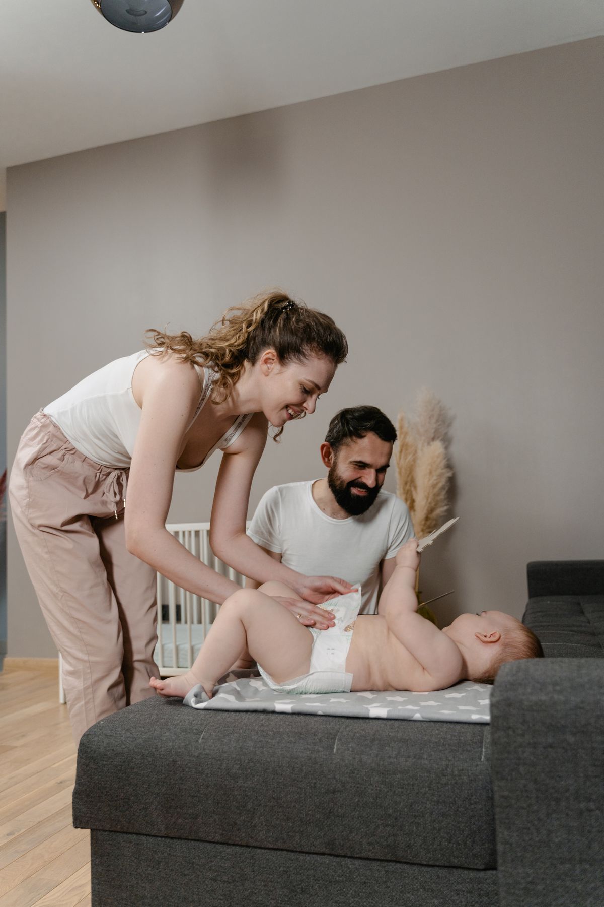 A parent laying a baby down on a changing pad to begin a diaper change