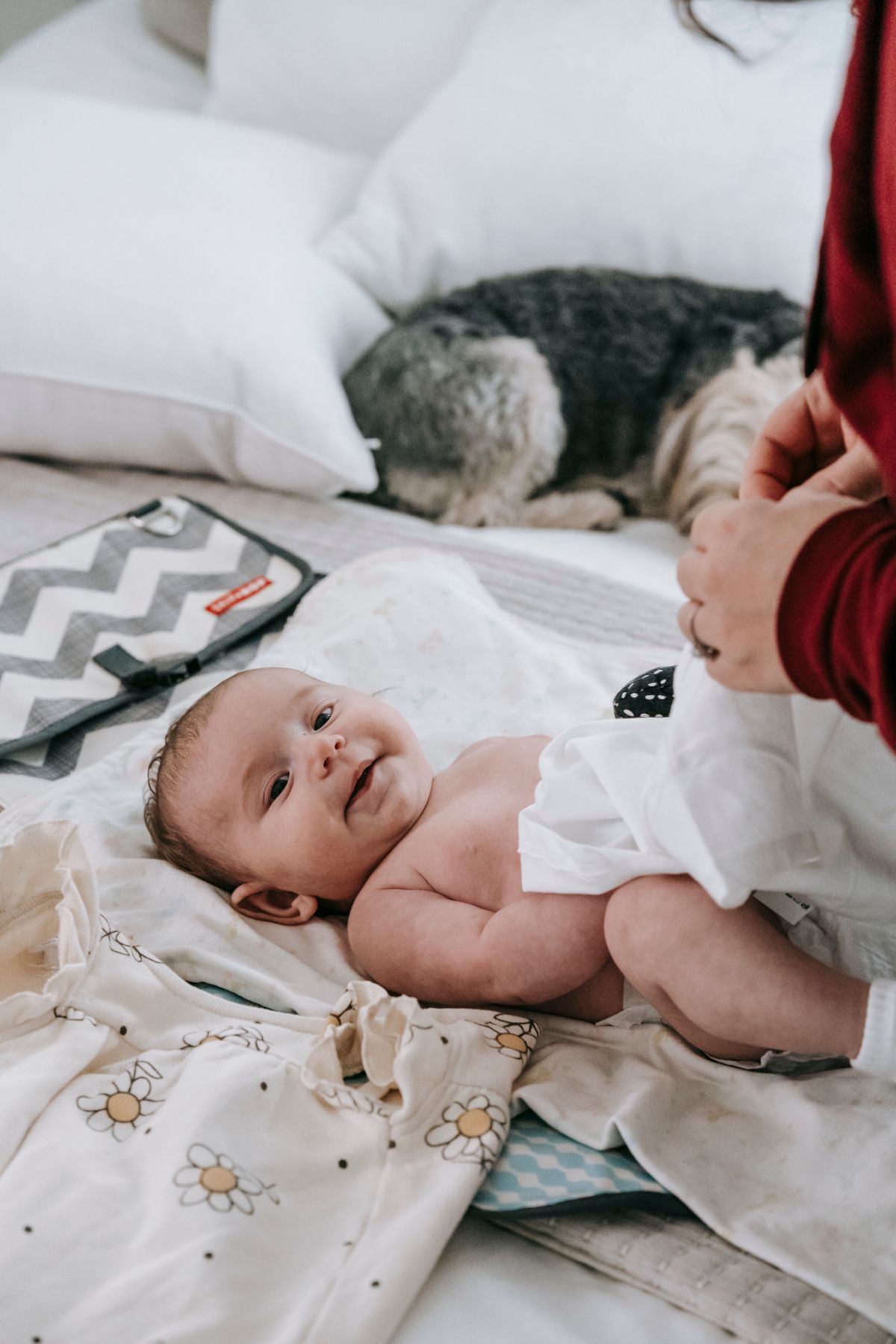A parent fastening a fresh diaper on a baby and dressing them