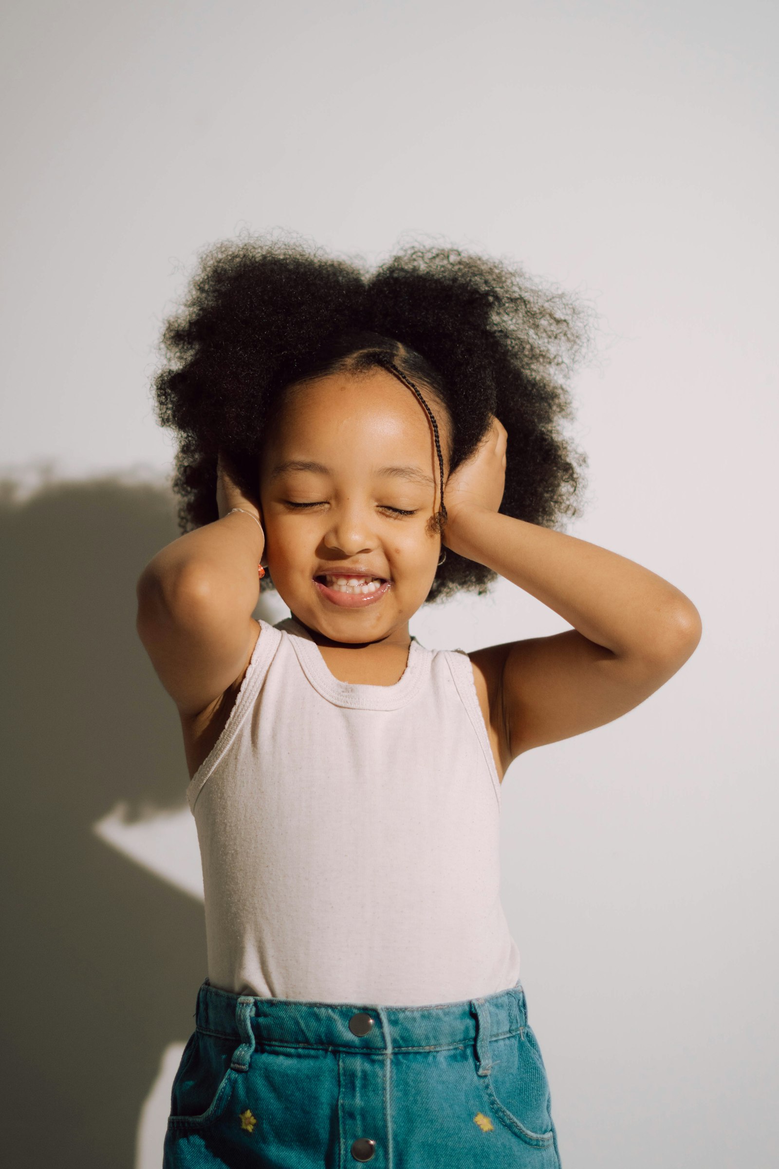 A young toddler covers her ears with her hands