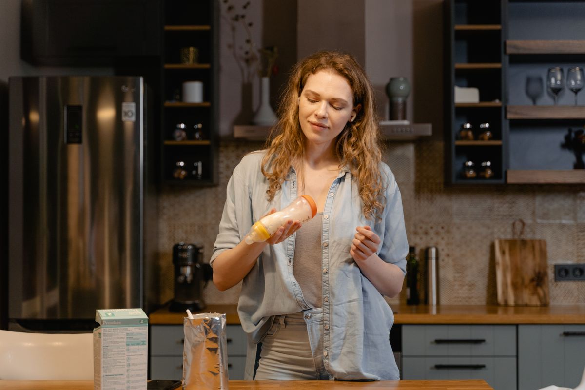 A parent preparing a bottle of formula in the kitchen