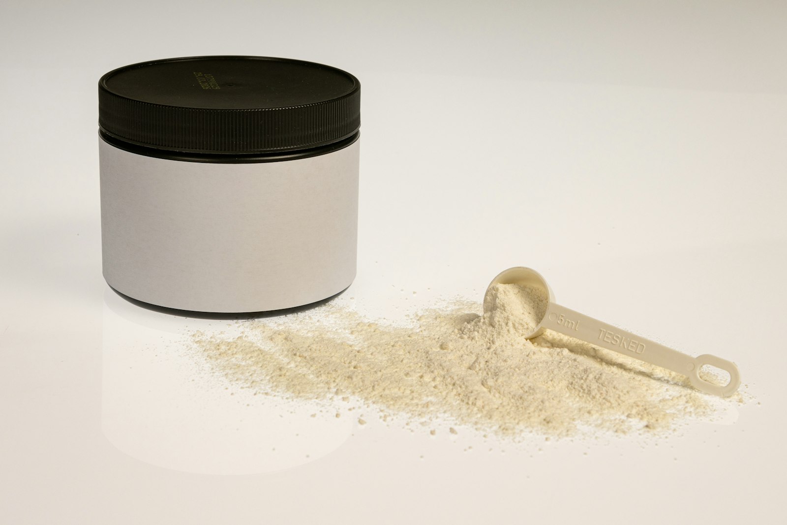A container of powdered formula with a measuring scoop