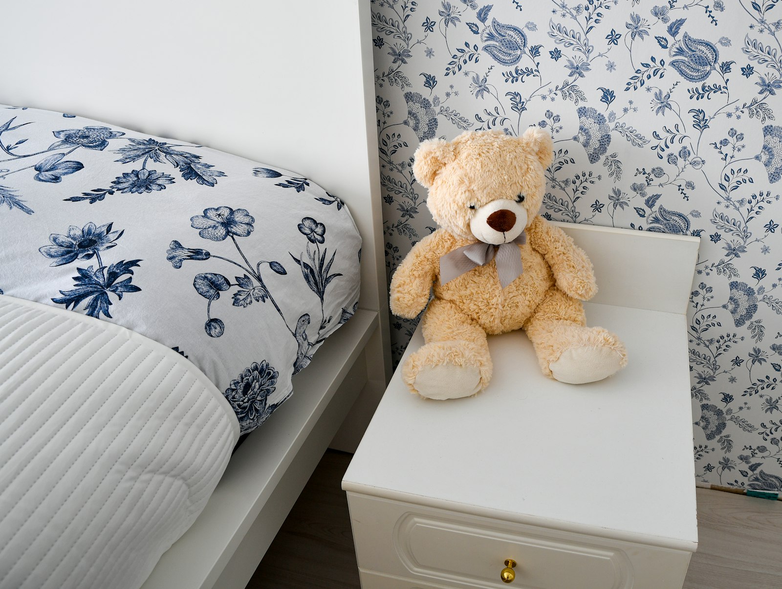 A cozy child's bed with a teddy bear on the nightstand