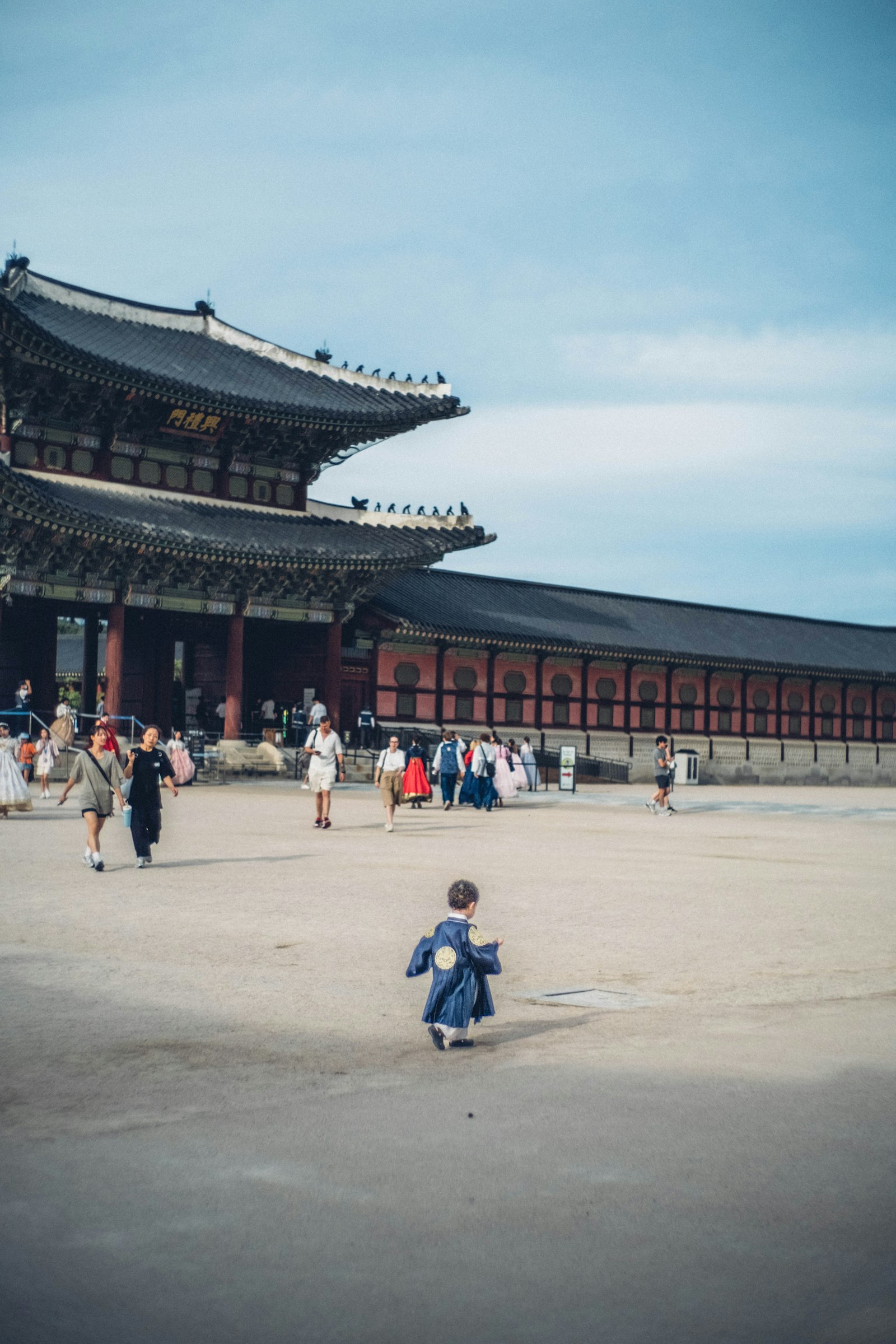 A child in traditional Korean hanbok walking near a palace