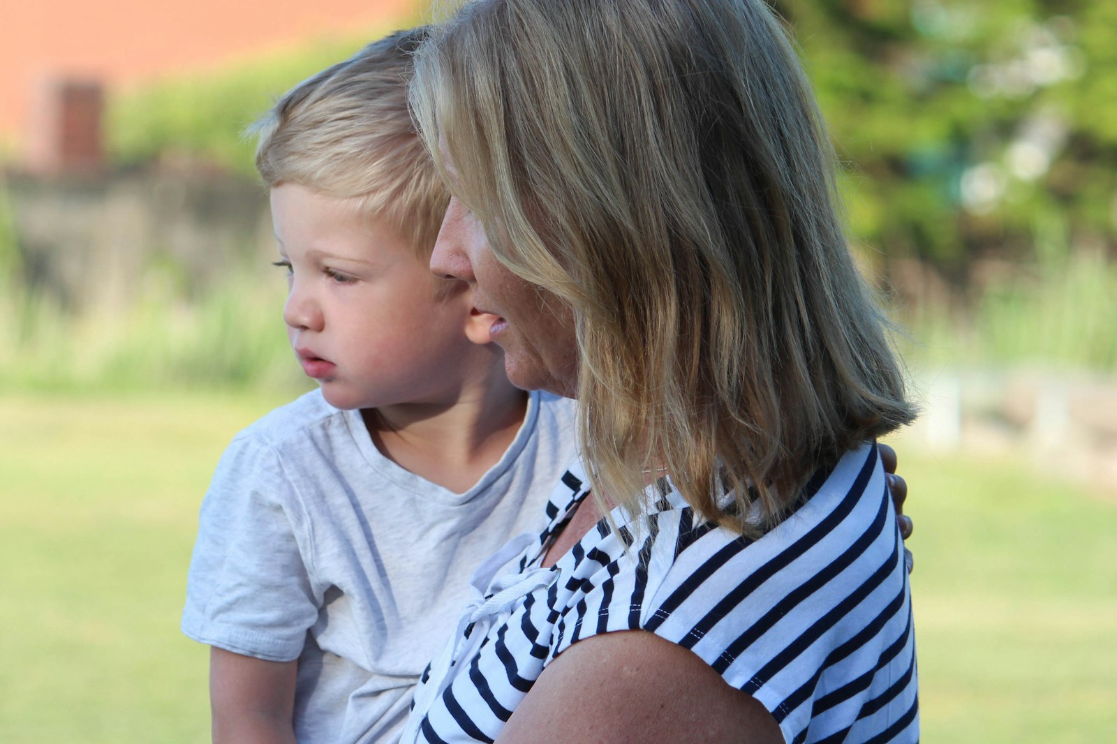 A mother holding her young child close in a tender outdoor moment