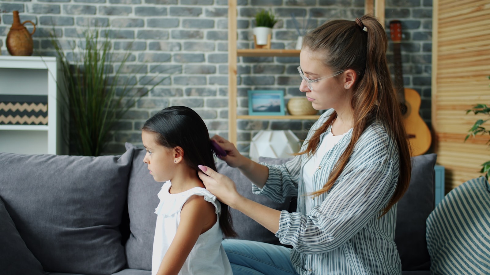 A mother gently combing her daughter's hair