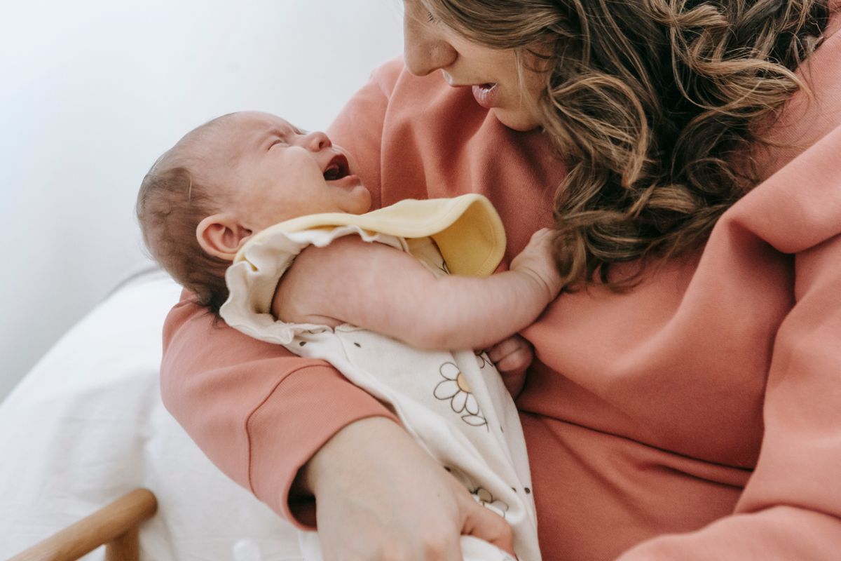 A mother gently soothing her crying baby in her arms