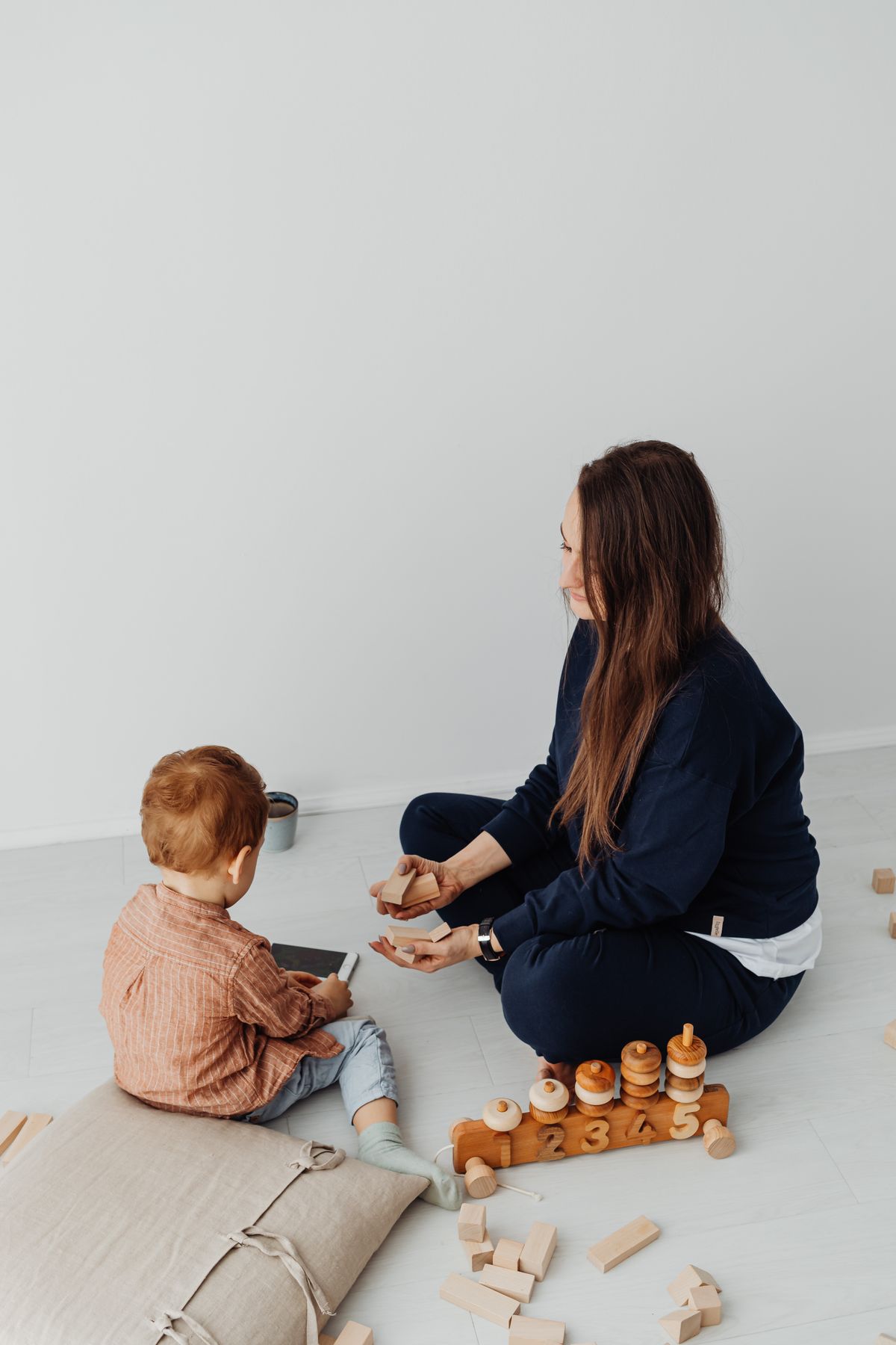 A mother sitting on the floor face to face with her toddler during play