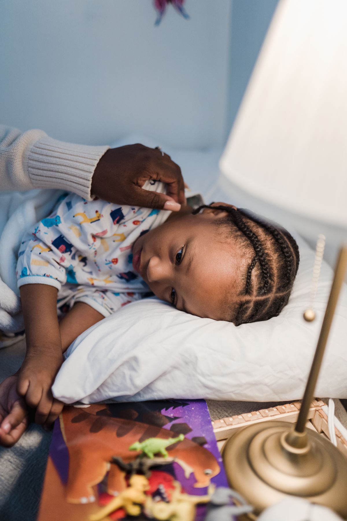 A mother tucking her young child into bed at night