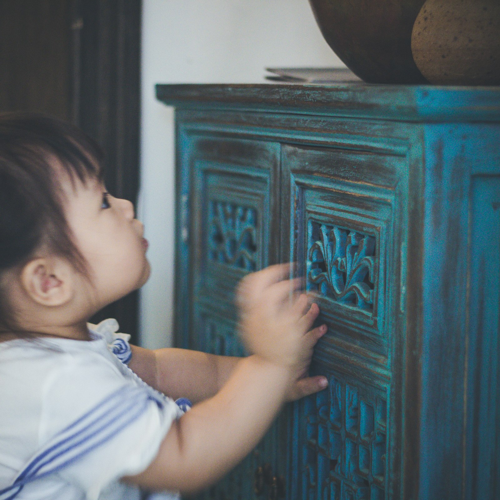 Toddler standing near a childproofed cabinet