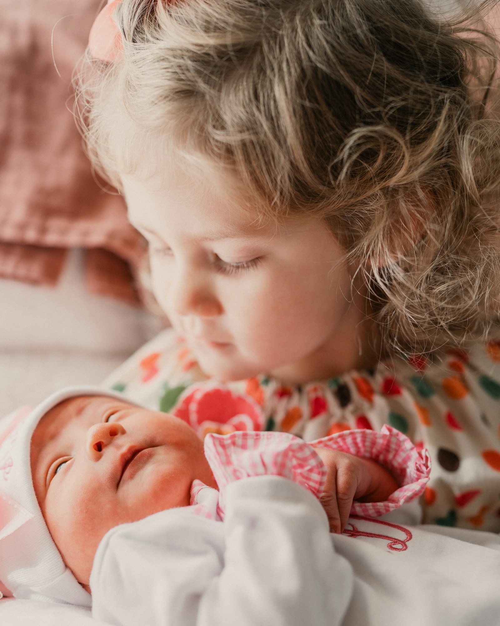 An older sister looks tenderly at her newborn baby sibling