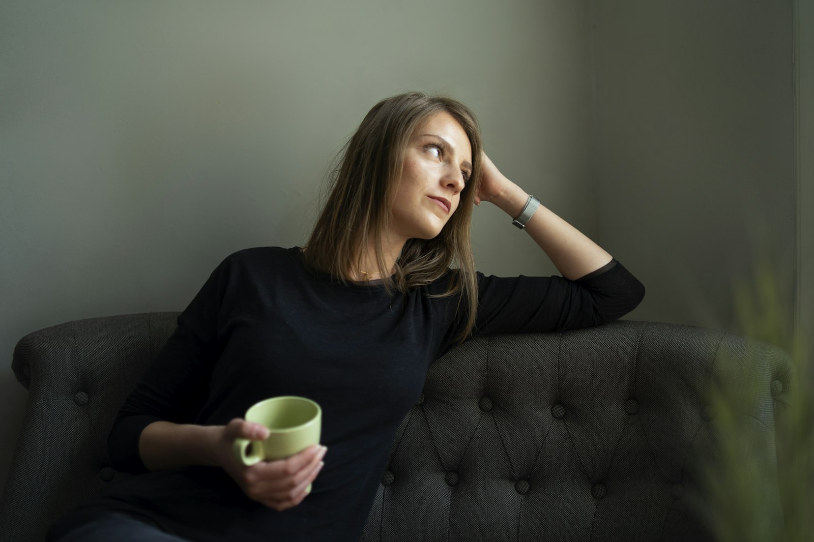A woman resting on a couch holding a mug