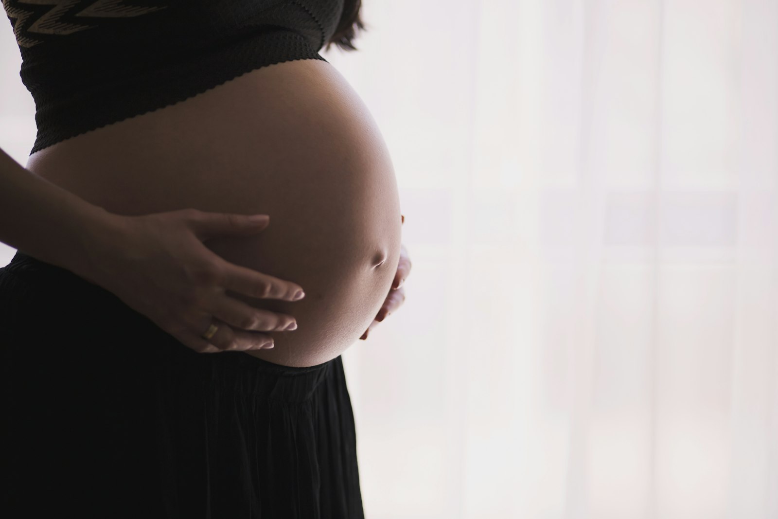 A pregnant woman gently cradling her belly