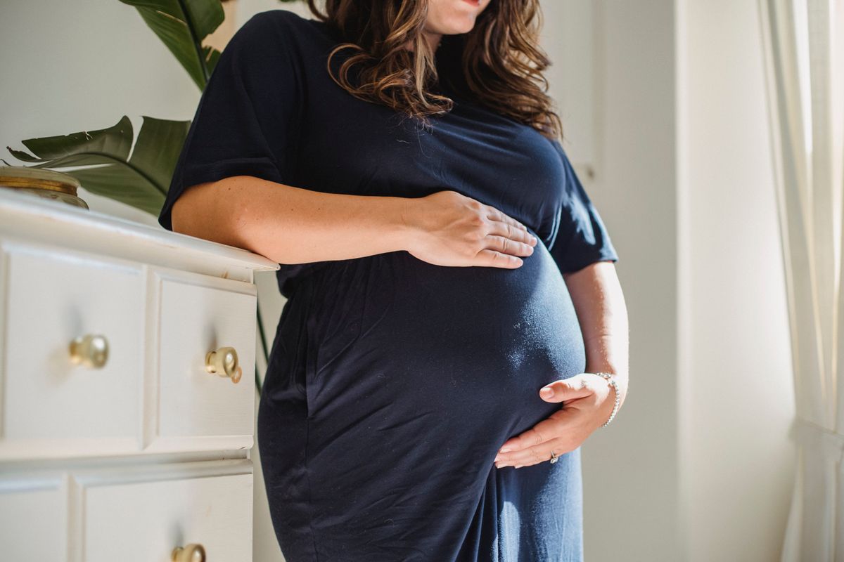 A pregnant woman with her hand resting on her chest