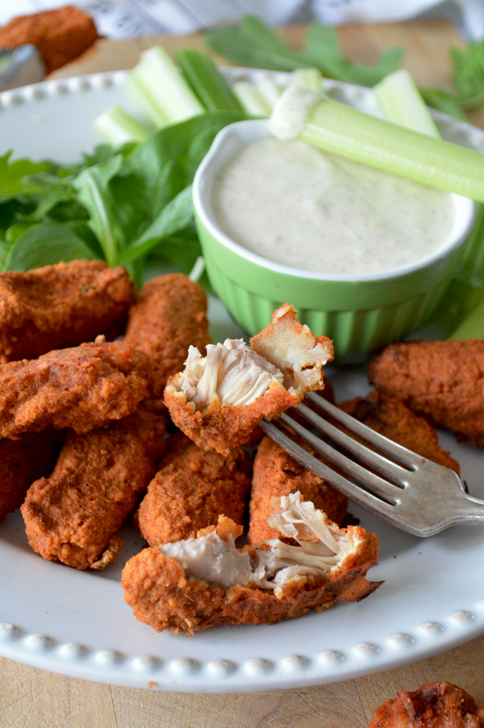 A plate of golden, crispy baked chicken nuggets with a dipping sauce