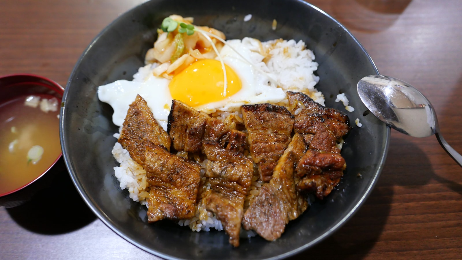 A bowl of grilled beef over rice with vegetables, Korean-style
