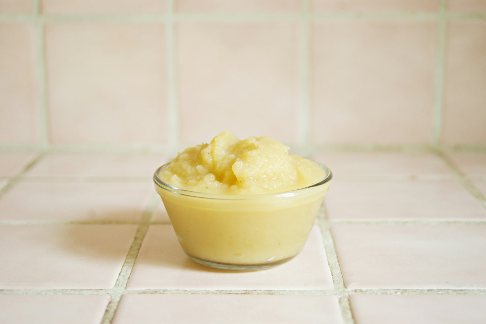 A smooth orange sweet potato and apple puree in a white bowl
