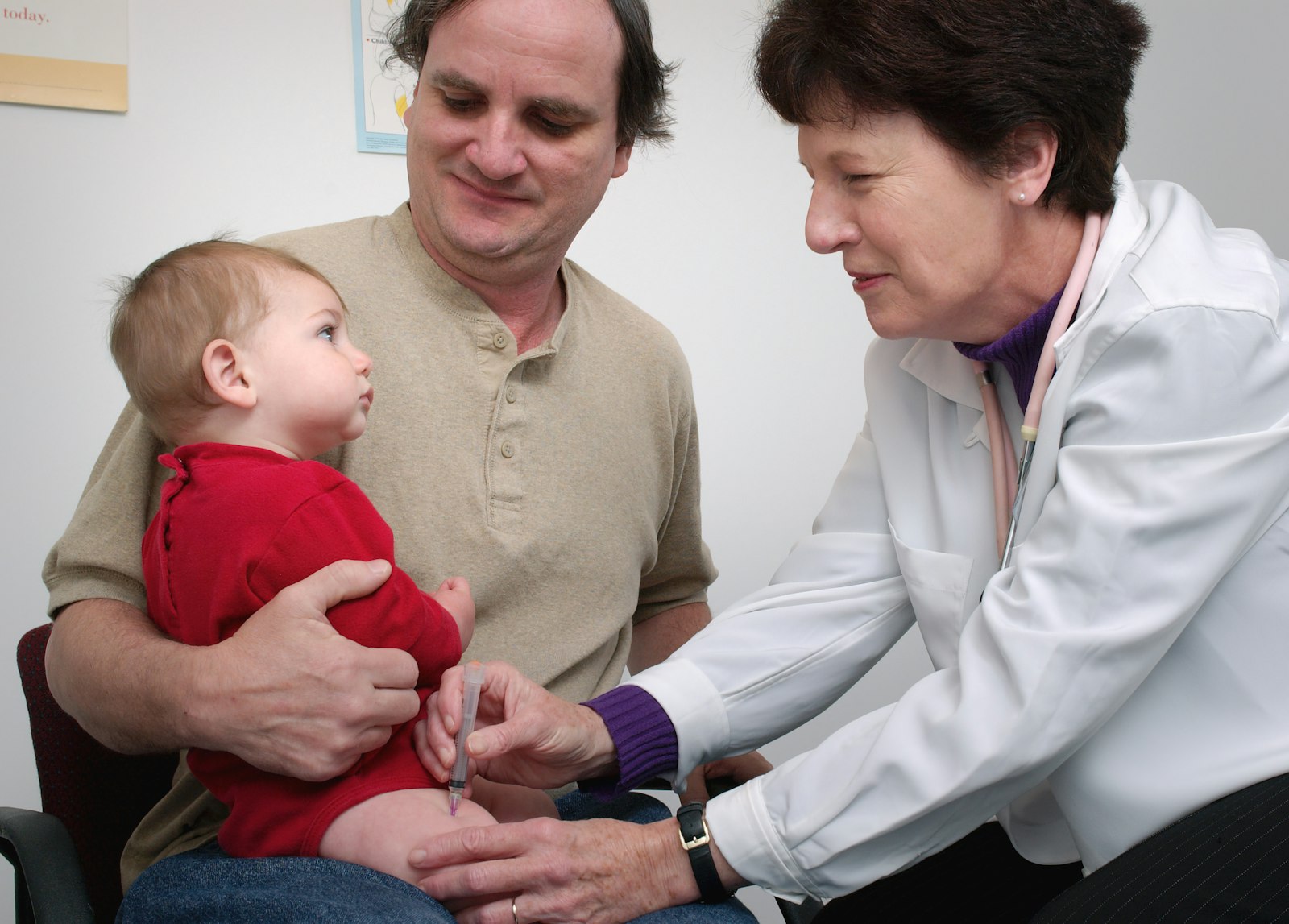 A pediatrician examines a baby held by a parent during a checkup