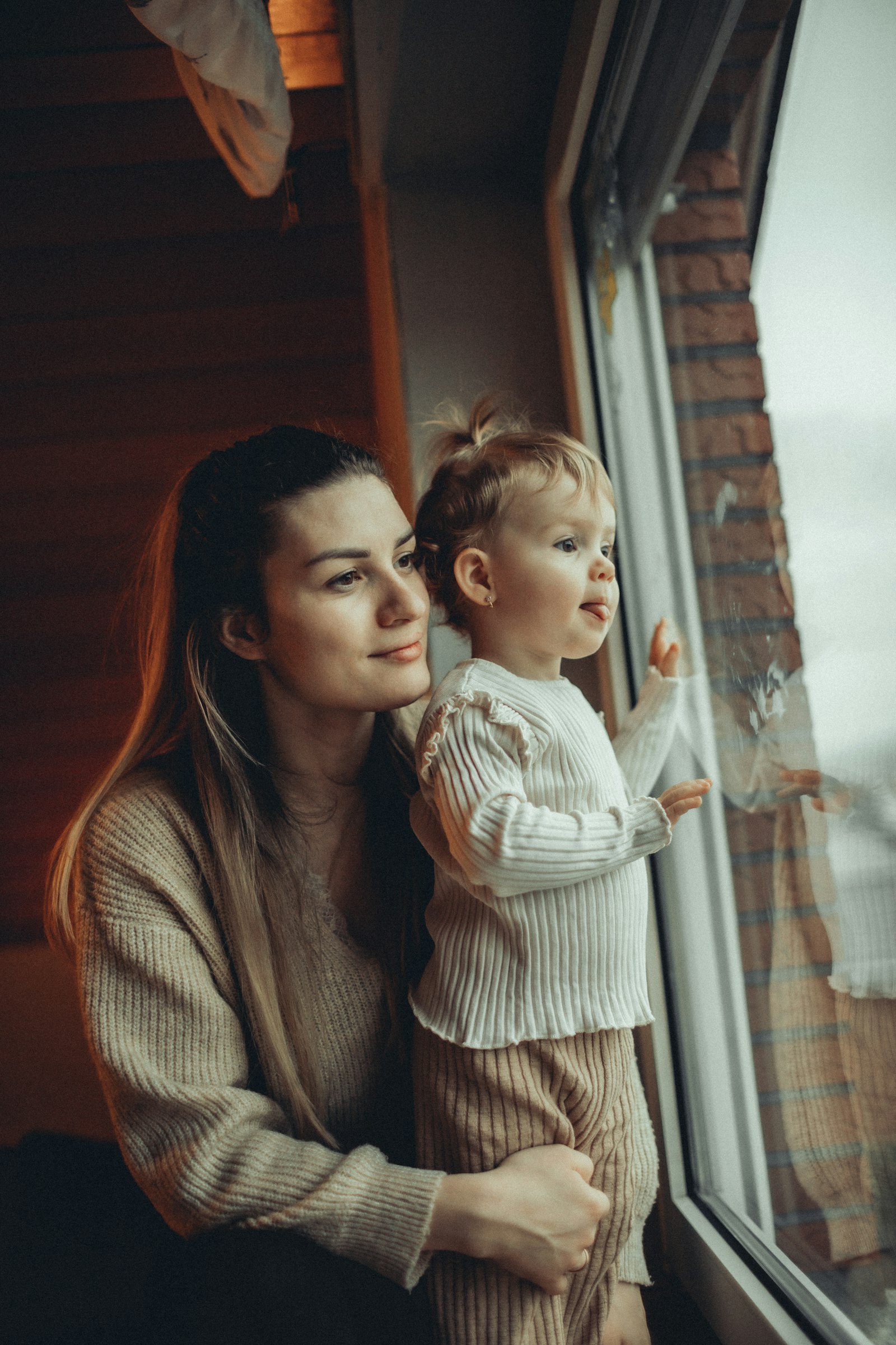 A mother and young child looking out a window together