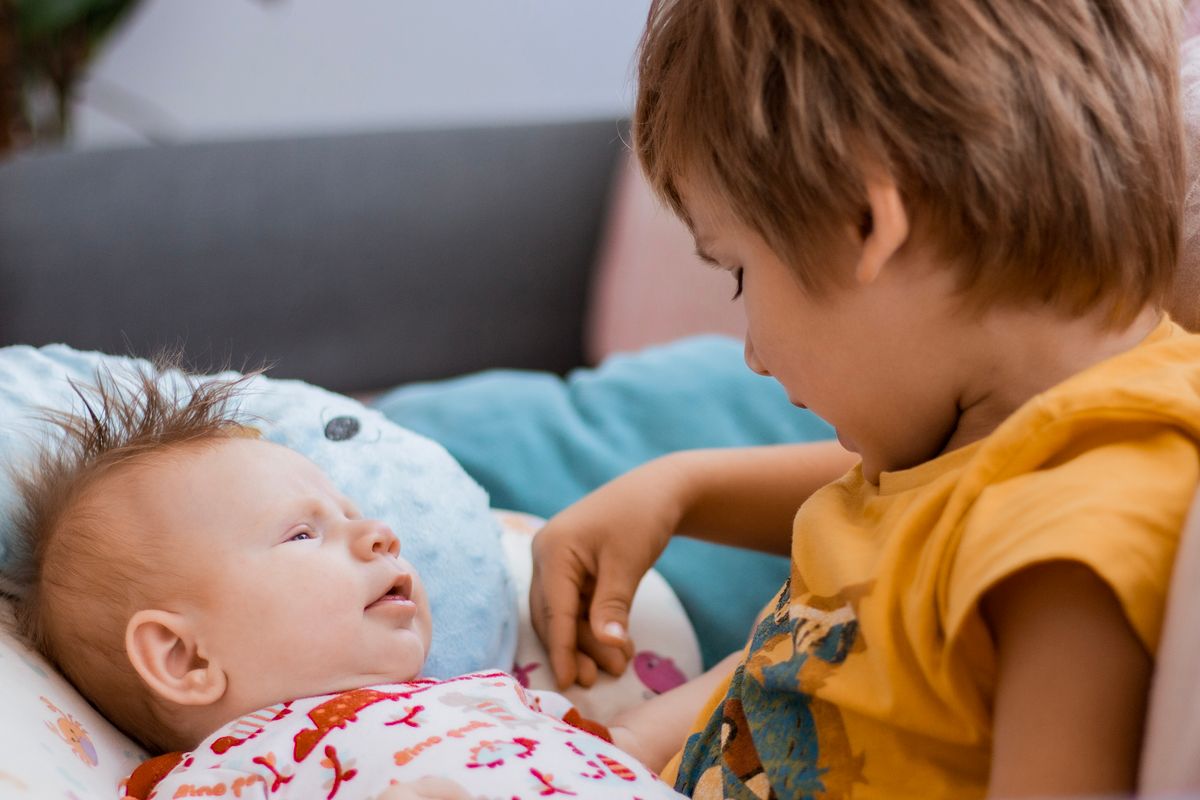 A young boy thoughtfully watching over a newborn baby